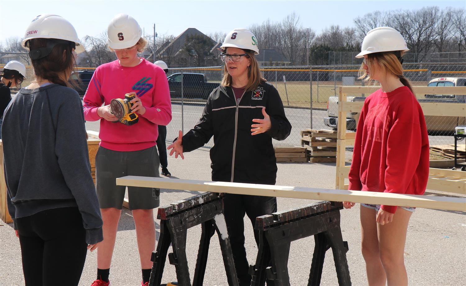 A teacher works with students on a segment of their bunk bed project