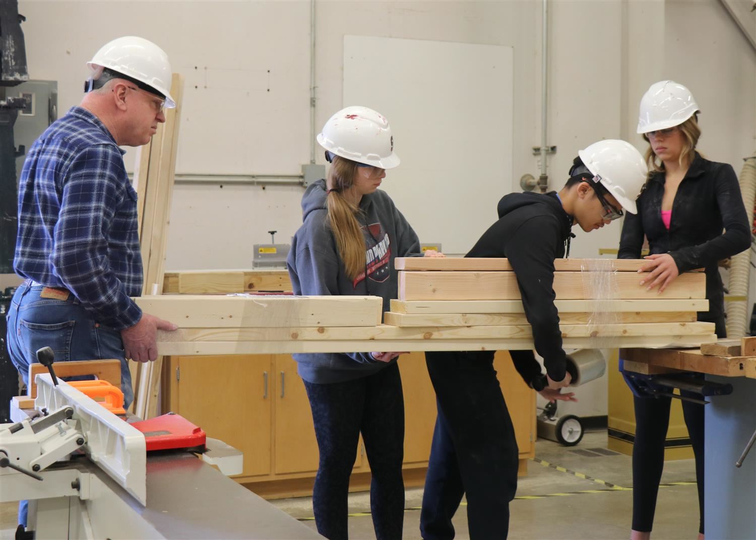 Students and a community member help wrap up wood in GIC class